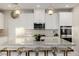 Modern kitchen features white cabinets, granite counters, stainless steel appliances, a stylish tile backsplash, and sleek pendant lighting at 864 Firestone Ledge Ave, Henderson, NV 89012