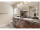 Well-lit bathroom offers dual sinks, granite counters, wood cabinets and a shower/tub combination at 9853 Russian Hill St, Las Vegas, NV 89141