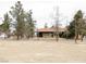 Large backyard with mature trees, tan single story home and gravel landscaping at 1081 Pluto St, Pahrump, NV 89048