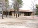 View of a tan single story home in backyard with mature trees at 1081 Pluto St, Pahrump, NV 89048