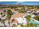Expansive aerial view showcasing neighborhood homes with tile roofs, mature palms and mountain views at 1600 Windsford Cir, Las Vegas, NV 89117