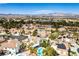 Scenic aerial of homes featuring pools, lush landscaping, and views of the surrounding mountains at 1600 Windsford Cir, Las Vegas, NV 89117