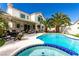 Resort-style backyard with refreshing pool, lush palm trees, and covered patio area at 1600 Windsford Cir, Las Vegas, NV 89117