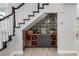 A stylish bar is tucked under the stairs with wood accents and wallpaper backdrop at 1600 Windsford Cir, Las Vegas, NV 89117