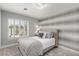 Comfortable bedroom featuring neutral colors, decorative wallpaper, and a window with bright natural light at 1600 Windsford Cir, Las Vegas, NV 89117
