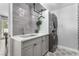 Modern laundry room with gray tiled wall, sink, cabinets, and stacked washer/dryer at 1600 Windsford Cir, Las Vegas, NV 89117