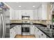 Updated kitchen boasts white cabinets, stainless steel appliances, and a black countertop at 2021 Summit Pointe Dr, Las Vegas, NV 89117