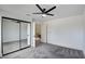 Spacious bedroom featuring plush gray carpet, mirrored closet doors, and a modern ceiling fan at 2716 Ferrin Rd, Las Vegas, NV 89117