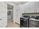 Well-equipped laundry room with gray washer and dryer, plus white cabinets and wood look flooring at 33 Hassayampa Trl, Henderson, NV 89052