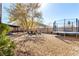 Spacious backyard with drought landscaping, a covered patio, seating area, and a trampoline at 432 Bottle Brush Way, Henderson, NV 89015