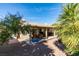Wide backyard showcasing a covered patio with outdoor seating, mature landscaping, and gravel ground cover at 455 Paulson Dr, Las Vegas, NV 89123