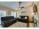 Cozy living room with dark sofas, ceiling fan, and a fireplace, perfect for relaxation at 455 Paulson Dr, Las Vegas, NV 89123