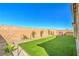 Well-manicured backyard is equipped with green turf, hardscape accents, and a playhouse and slide set at 6593 Corsari Ridge St, Las Vegas, NV 89166