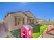 Cozy backyard with a playhouse and slide set, along with green turf and a low-maintenance landscape design at 6593 Corsari Ridge St, Las Vegas, NV 89166