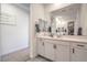 Bright bathroom vanity featuring white cabinetry, quartz counters, and a large mirror reflecting into the walk-in closet at 6593 Corsari Ridge St, Las Vegas, NV 89166