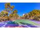A well-maintained tennis court is surrounded by trees under a brilliant, cloudless sky at 725 N Royal Crest Cir # 227, Las Vegas, NV 89169