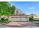 Beautiful home featuring a three-car garage, lush green lawn, desert landscaping, and a brick paved driveway at 7333 Painted Shadows Way, Las Vegas, NV 89149
