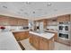 Spacious kitchen with wood cabinetry, stainless steel appliances, and a center island with a cooktop at 7333 Painted Shadows Way, Las Vegas, NV 89149