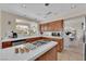 Well-lit kitchen with wood cabinets, an island cooktop, and an adjacent dining area at 7333 Painted Shadows Way, Las Vegas, NV 89149