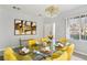 Well-lit dining room with a glass table, yellow chairs, and elegant decor, adjacent to exterior view at 7925 Limbwood Ct, Las Vegas, NV 89131