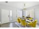 Dining room with yellow chairs, glass table, chandelier, and natural light, creating a welcoming space at 7925 Limbwood Ct, Las Vegas, NV 89131