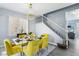 Chic dining room featuring a glass table, yellow velvet chairs, and stairway access, creating an inviting atmosphere at 7925 Limbwood Ct, Las Vegas, NV 89131