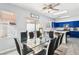 Bright dining room features a glass table with modern chairs, adjacent to a kitchen with blue cabinetry at 7925 Limbwood Ct, Las Vegas, NV 89131