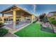 Manicured backyard with outdoor kitchen, dining area, and a relaxing swing at 8298 W Agate Ave, Las Vegas, NV 89113
