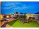 Backyard featuring a fire pit, lounge chairs, green grass, and manicured landscaping, perfect for relaxation at 8298 W Agate Ave, Las Vegas, NV 89113