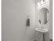 Neutral-toned half bath with classic pedestal sink, round mirror, and modern lighting at 9233 Far Side Ave, Las Vegas, NV 89143