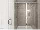 Close-up of a tiled shower with a glass door and a chrome shower head and handle at 9233 Far Side Ave, Las Vegas, NV 89143