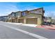 Exterior view of townhomes with multiple car garages, layered roofing, and a sidewalk at 965 Nevada State Dr # 36102, Henderson, NV 89002