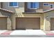 Attached one-car garage door with lights, rock detail, and a walkway, on a sunny day at 965 Nevada State Dr # 36102, Henderson, NV 89002