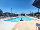 Community pool with accessibility lift, lounge chairs, covered patio, and a glimpse of the neighborhood at 965 Nevada State Dr # 36102, Henderson, NV 89002