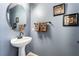 Stylish powder room features a pedestal sink, decorative mirror, and modern fixtures at 10435 Meadow Village St, Las Vegas, NV 89183