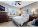 Bright bedroom features a queen-size bed, neutral decor, ceiling fan, and window letting in natural light at 10435 Meadow Village St, Las Vegas, NV 89183