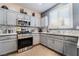 Modern kitchen with stainless steel appliances, gray cabinets, granite countertops, and stylish backsplash at 10435 Meadow Village St, Las Vegas, NV 89183