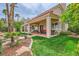 A lush backyard with mature trees and stone landscaping features a covered patio with comfortable seating at 138 Wentworth Dr, Henderson, NV 89074