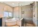 Bright bathroom featuring a soaking tub and a tiled walk-in shower behind glass panel at 20 High Sierra Dr, Henderson, NV 89074