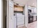 Laundry closet with light wood cabinets, washer, and dryer next to kitchen cabinets at 2836 Floral Peak Dr, Henderson, NV 89074