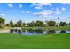 Scenic golf course view with lush green grass, tranquil pond, and beautiful homes in the background at 2861 Queens Courtyard Dr, Las Vegas, NV 89109