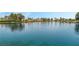 Picturesque lake view showcasing calm water reflecting nearby residential properties and lush green trees against a clear blue sky at 3151 Soaring Gulls Dr # 1049, Las Vegas, NV 89128