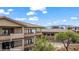 A modern condo with balconies is nestled among green trees with mountain views under a partly cloudy sky at 405 Paradise Pkwy # 170, Mesquite, NV 89027