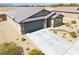 Exterior elevation featuring desert landscaping, gray two car garage, and tile roof at 5360 S Chippewa St, Pahrump, NV 89061