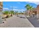 Expansive backyard featuring desert landscaping, a brick fire pit, and palm trees at 6116 Golden Saddle St, Las Vegas, NV 89130