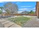 Grassy backyard features desert landscaping, trees, and gravel at 6116 Golden Saddle St, Las Vegas, NV 89130