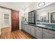 Spa bathroom features gray cabinets, dual sinks, dark countertops, wood-look floors, and a barn door at 6907 May Basket Ave, Las Vegas, NV 89131