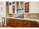Gourmet kitchen features designer backsplash, stainless hood vent, cooktop, granite countertops and custom cabinets at 6907 May Basket Ave, Las Vegas, NV 89131
