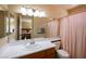 Bright bathroom with a large mirror, vanity, and a shower featuring a pink curtain, and a view into a bedroom at 8582 Manalang Rd, Las Vegas, NV 89123