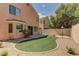 Lush backyard with artificial turf, decorative rock, and mature trees offering a private outdoor space at 8980 High Horizon Ave, Las Vegas, NV 89149